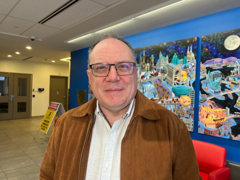 A man wearing glasses and grinning.