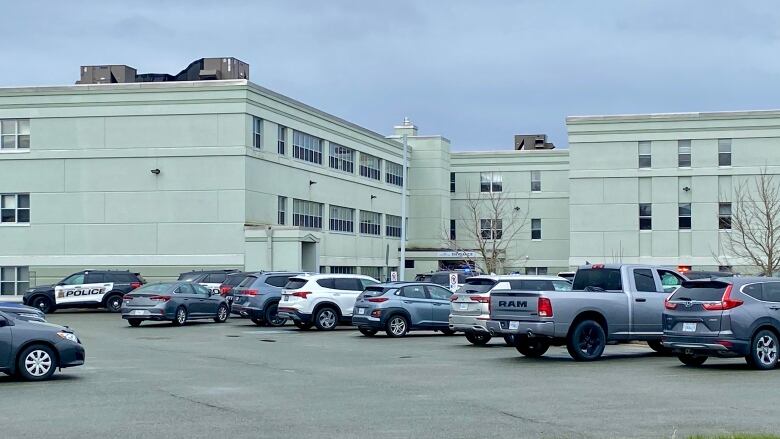 Cars are parked in a parking lot in front of a grey concrete building.