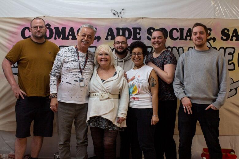 Four men and three women stand together smiling. 