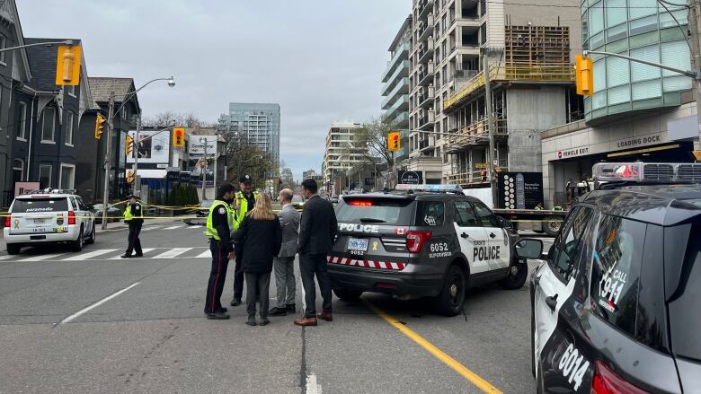 A group of people stand next to police cars at the scene of an accident.