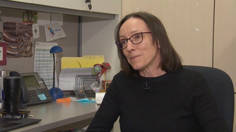 A woman sits at her desk.