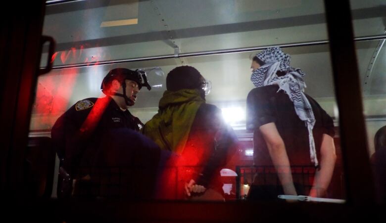 Members of the NYPD strategic response team load arrested protesters from Columbia University onto a bus on Tuesday evening.