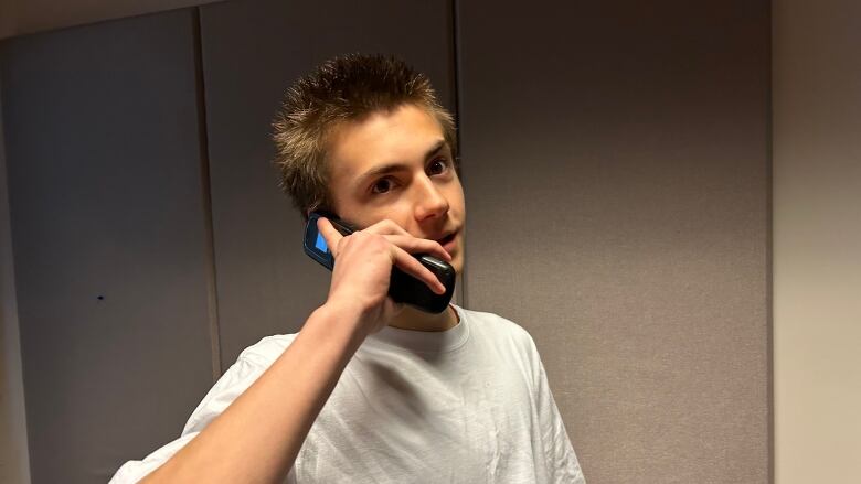 A teenager with a phone held to his ear.