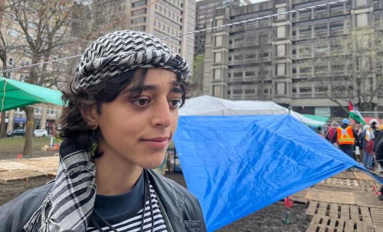 A woman with short hair and a keffiyeh scarf wrapped on her head