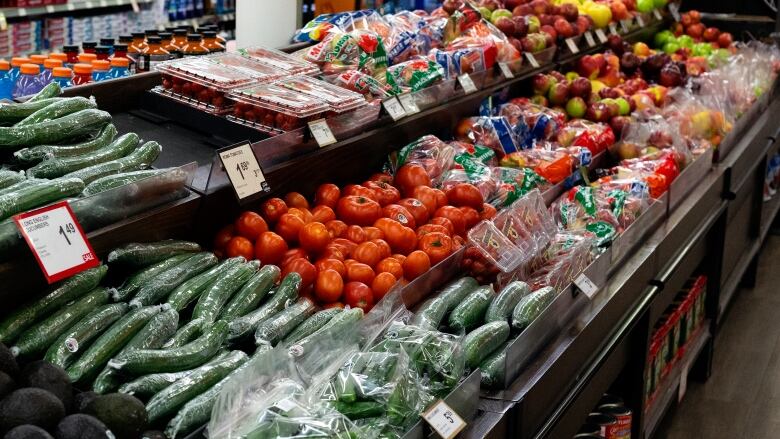 Cucumbers, tomatoes and other vegetables on display in a grocery store.