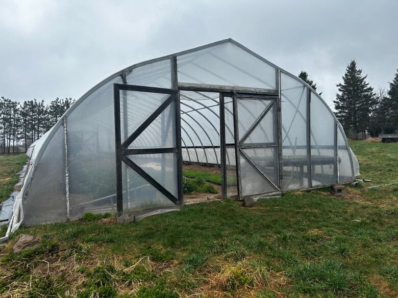 A white, translucent structure sits on green grass. Inside are plants.