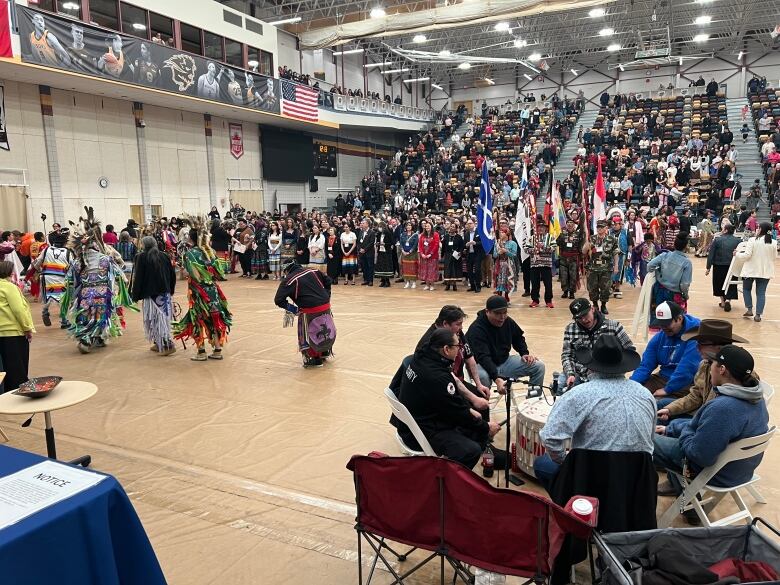 A crowd watches traditional Indigenous dancers and drummers perform.