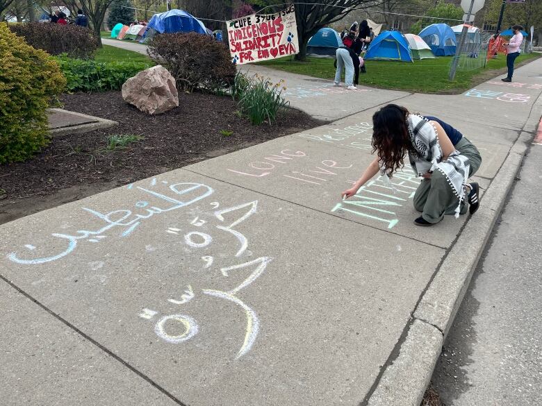 A person using chalk on a sidewalk.