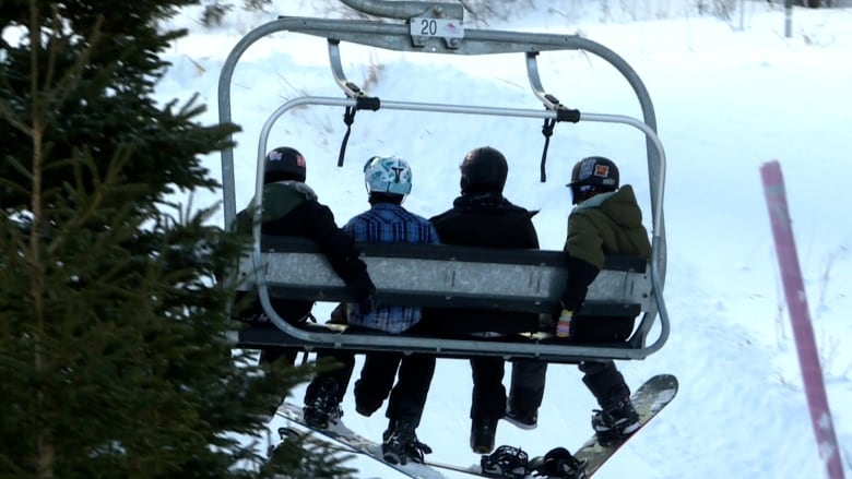 people riding a chairlift up a mountain. 