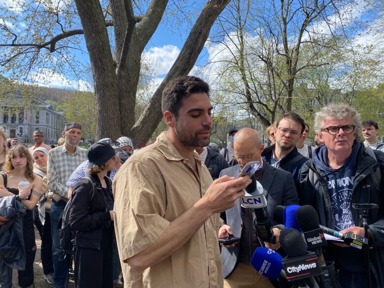 A professor speaks with reporters at the encampment. 