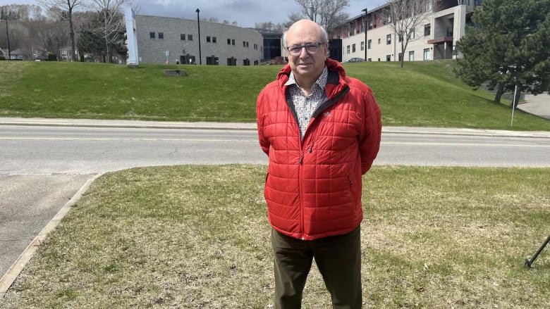 Man wearing red coat stands near road