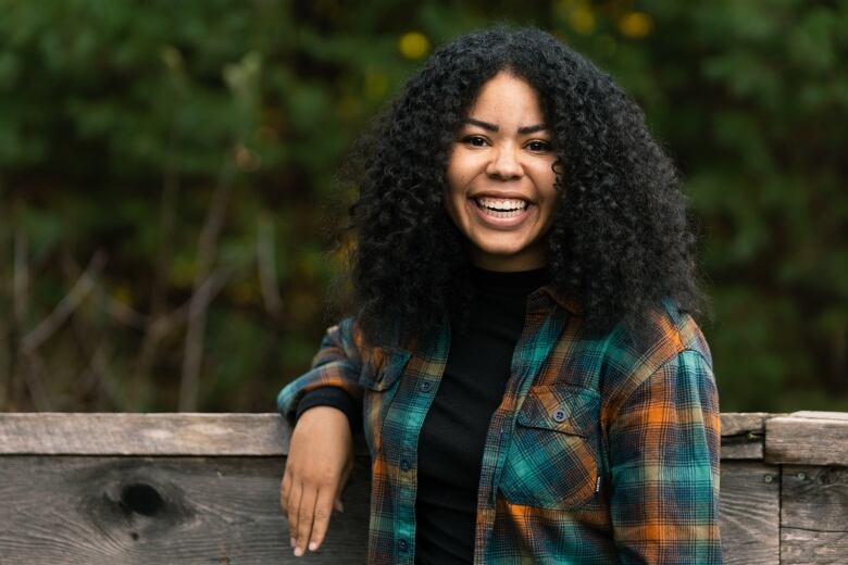 A woman wearing a plaid shirt smiles for a portrait photo.