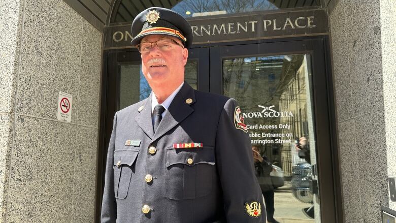 A man dressed in a dark uniform is shown outside a building.