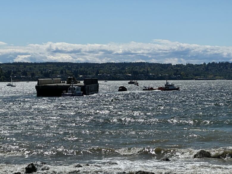 A large barge is seen being towed by boats.