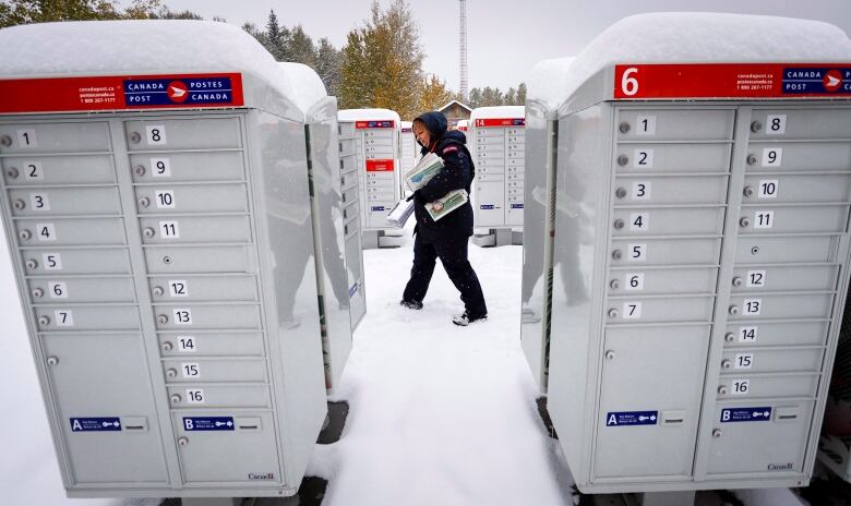 Canada Post employee Shelly Paul delivers the mail in snowy Water Valley, Alta., Tuesday, Oct. 2, 2018. Snowfall with total amounts of 10 to 20 cm are expected in south western Alberta.