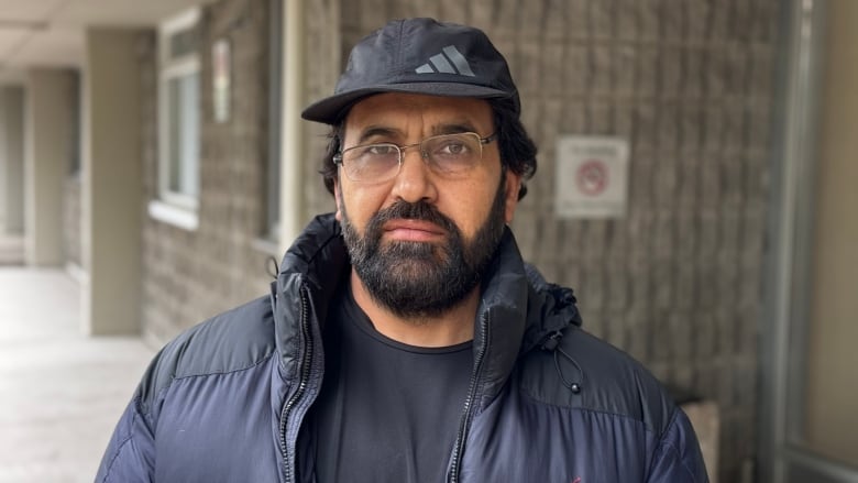 A man stands in front of an apartment.