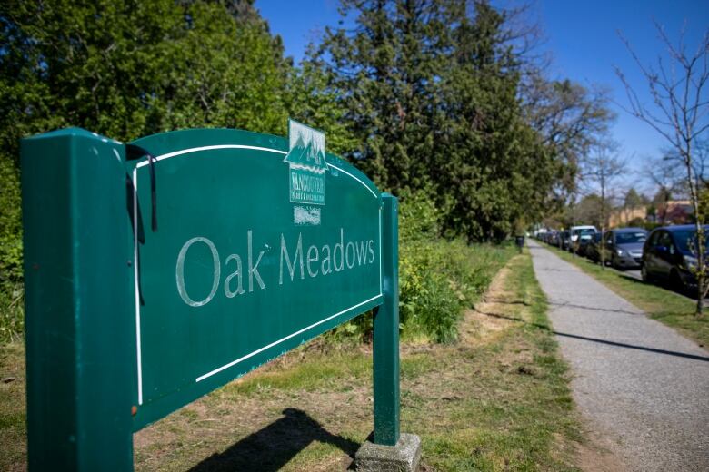 A sign reading 'Oak Meadows' next to a patch of green grass.