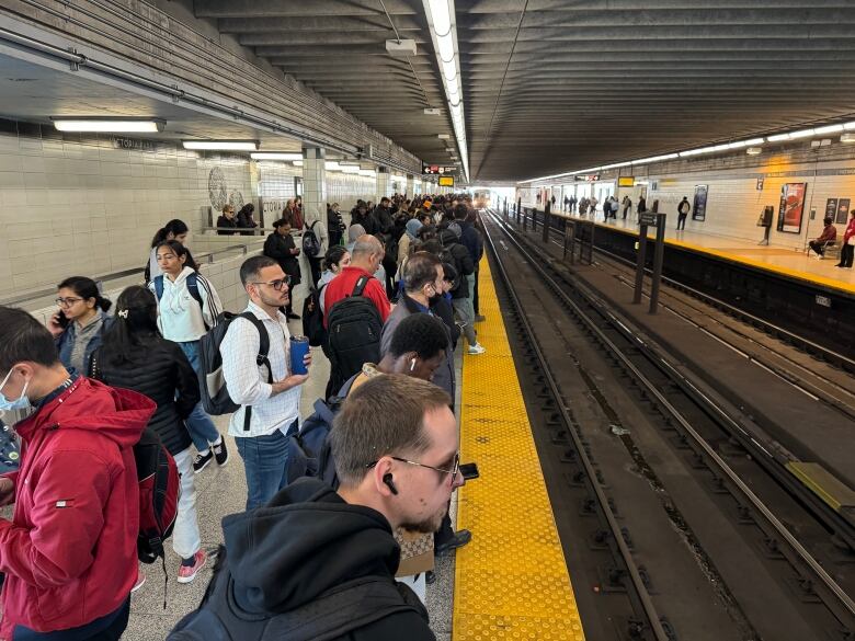 Passengers seen lined up along subway tracks at Victoria Park subway station.