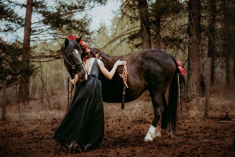 Woman leads into black horse with a white star on her head.