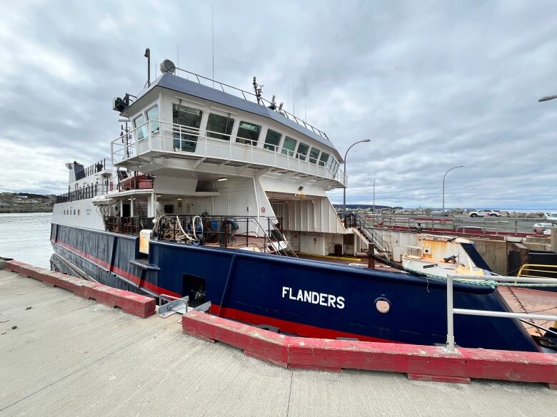 A blue and white ferry is docked at a pier.