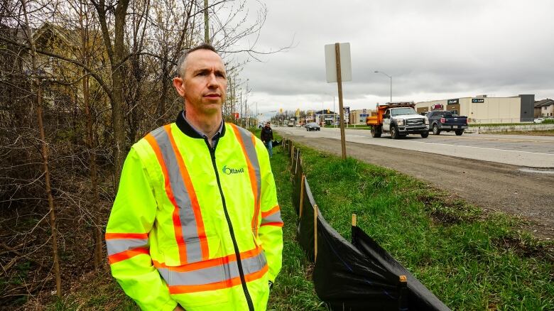 A project manager outside in spring, wearing a reflective yellow jacket.