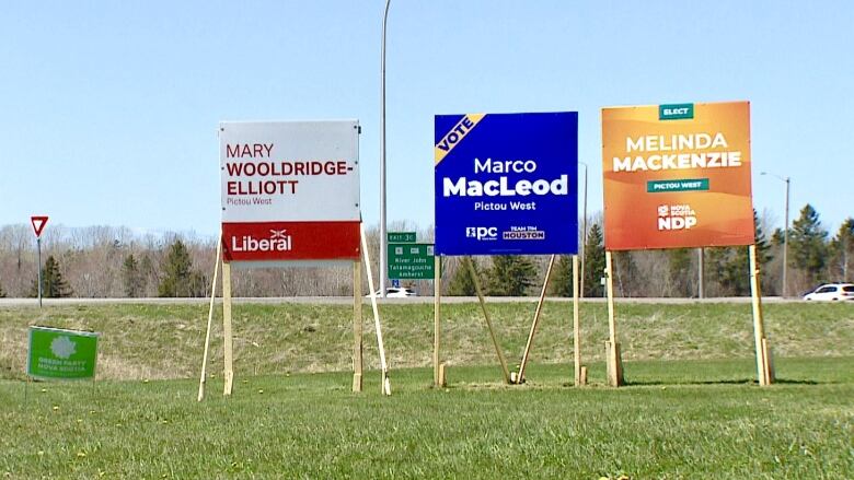 A street sign near a roundabout in Pictou County is accompanied by a small green party signs and large ones in support of the liberal, progressive conservative and ndp parties. 