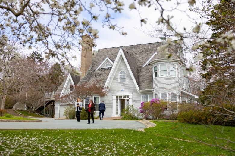 Two people stand in front of a large house.