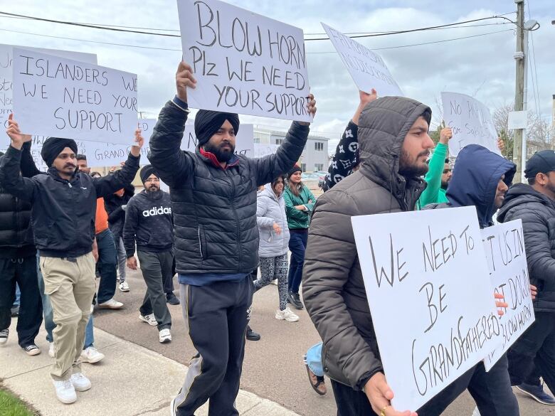 People march while holding signs.