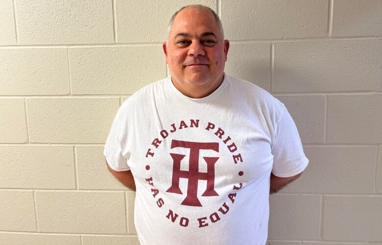 A white man with grey hair, wearing white t-shirt.