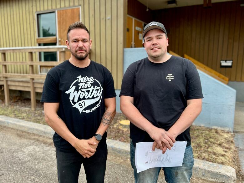 Two men smiling in front of a town hall