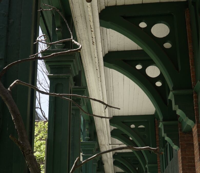 Forest green beams punctuate a veranda