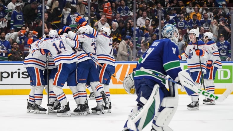 Hockey players celebrate while a goalie skates off sadly.