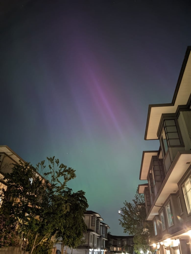 Northern lights are seen above apartment buildings.