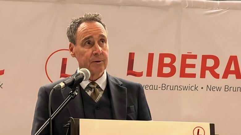 A man stands in front of a Liberal sign.