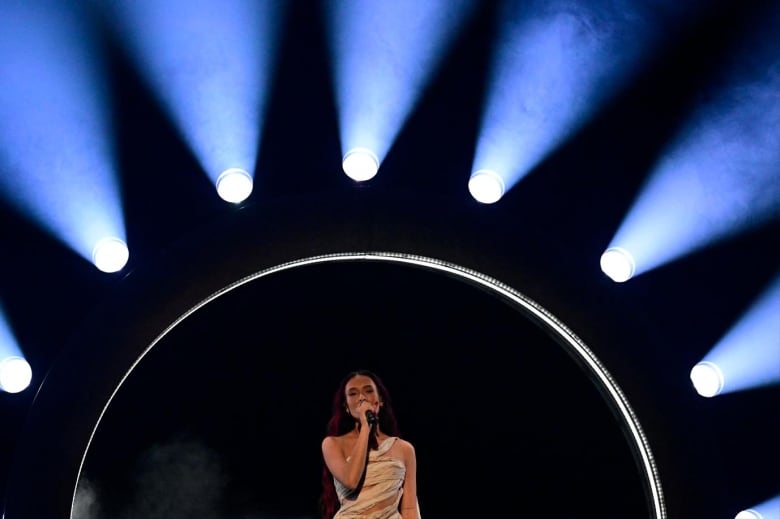 A singer performs in front of a ring of lights.