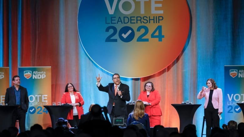 A politician gestures while speaking as others look on.