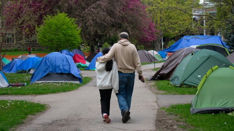 A man and child walking near tents.