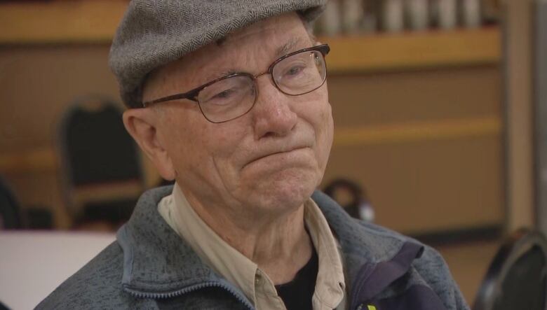 An older man in a hat has an expression of crying.