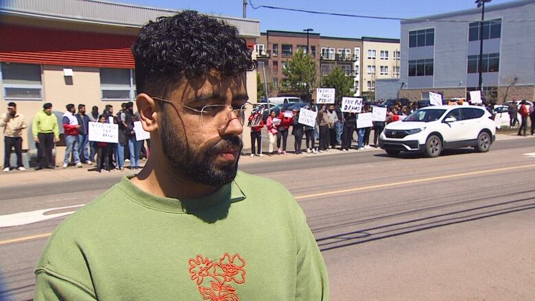 Man standing on sidewalk with crowd behind him.