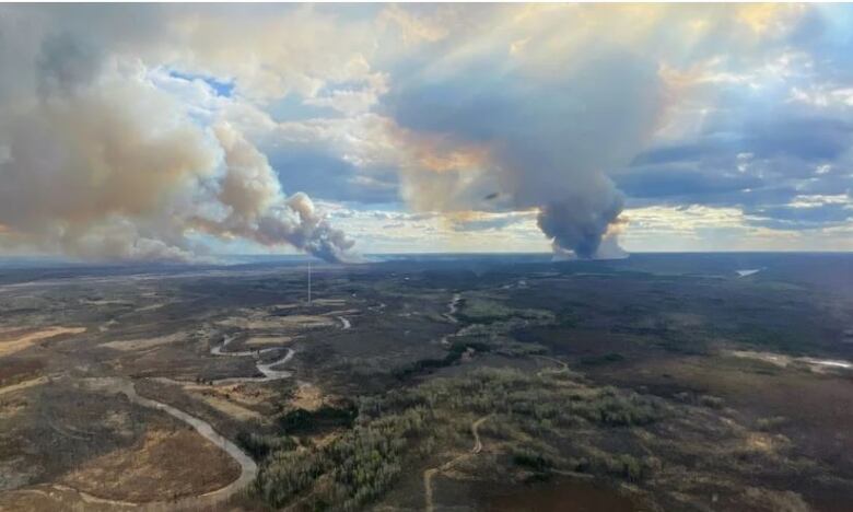 An aerial view of a wildfire. Smoke is visible on the horizon.