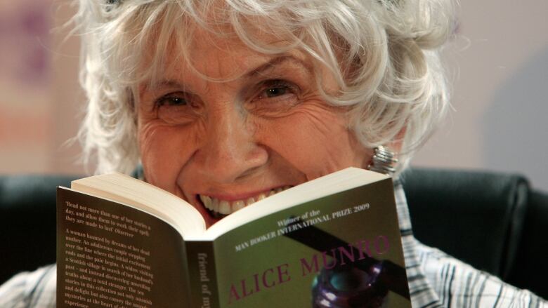 Alice Munro holds one of her books up to her face, in a closeup still of the author.