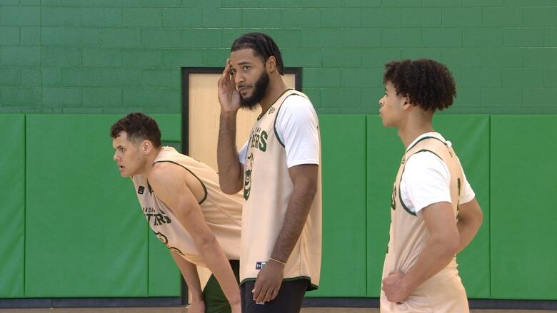 Three basketball players in a gym.