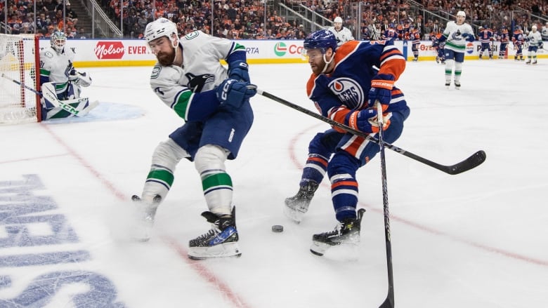 Two hockey players battle for the puck.