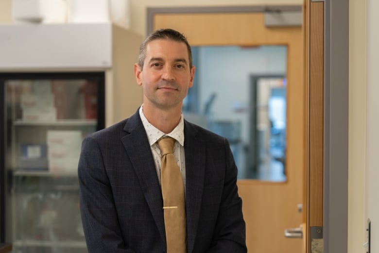 A man in a suit poses for a photo in a hospital laboratory.