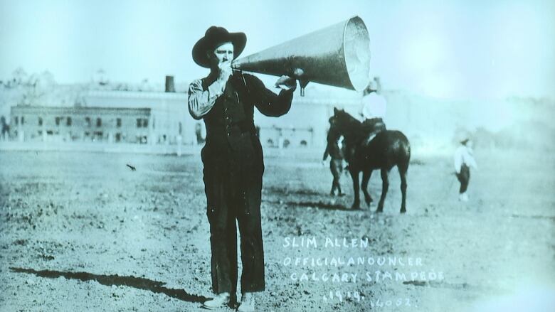 A man holds a megaphone in a black and white photograph. 