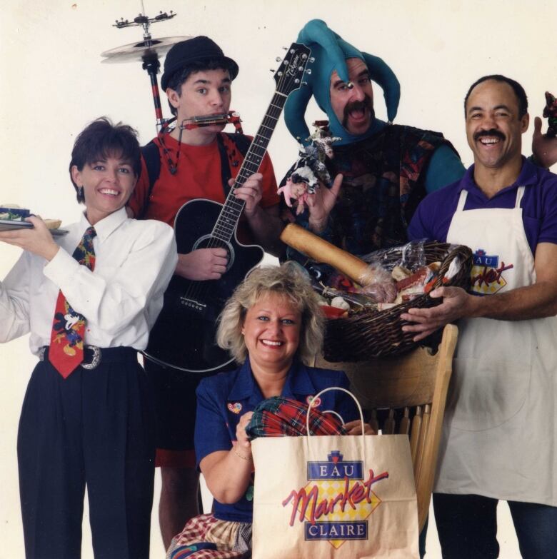 Two street performers pose with workers from a Calgary mall. There is a white background.