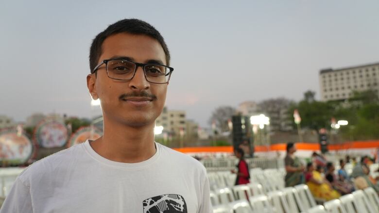 A man in a white T-shirt and black glasses.