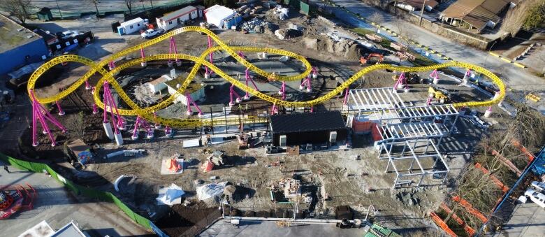 A yellow roller coaster track is seen here amid other construction materials