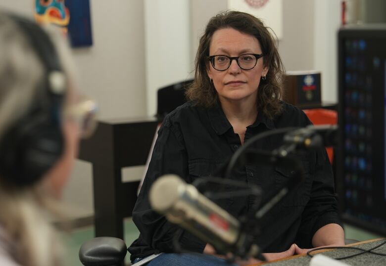 Two women sit talking in a radio studio.