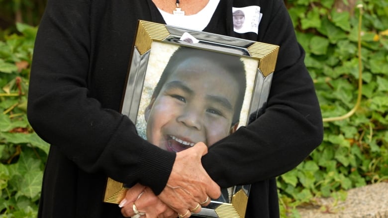 woman holds large photo of smiling boy